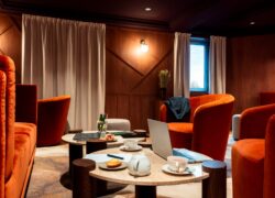 un espace ciné lounge loué comme salle de réunion insolite, avec un ordinateur sur table basse, du thé, des madeleines et une veste de costume posée sur un fauteuil