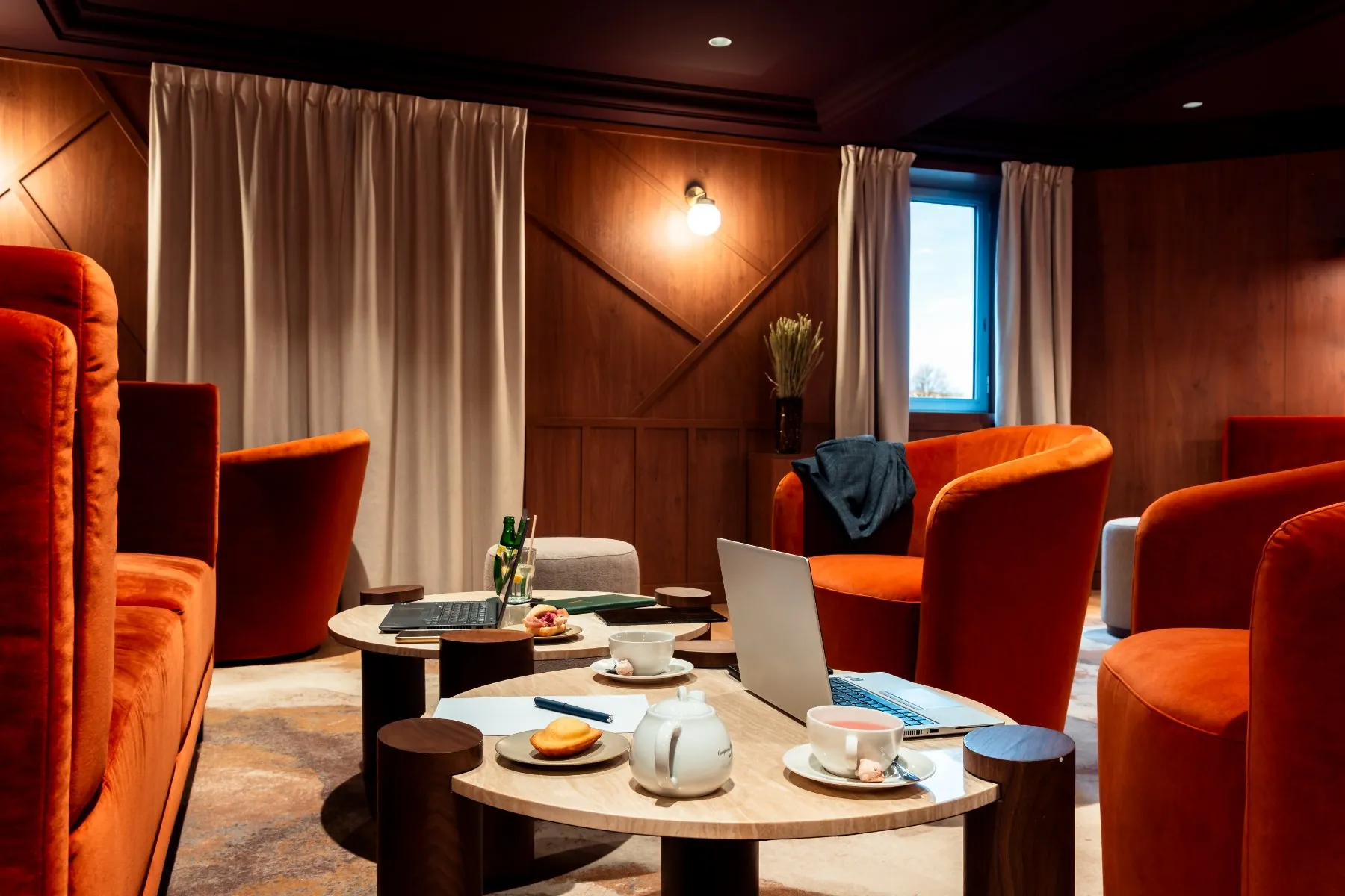 a cinema lounge area rented as an unusual meeting room, with a laptop on a coffee table, tea, madeleines, and a suit jacket on an armchair