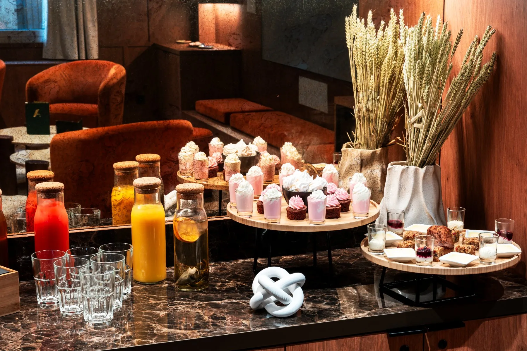 a cinema lounge area rented as an unusual meeting room, focusing on a sweet break setup with fruit juices, pastries, and verrines
