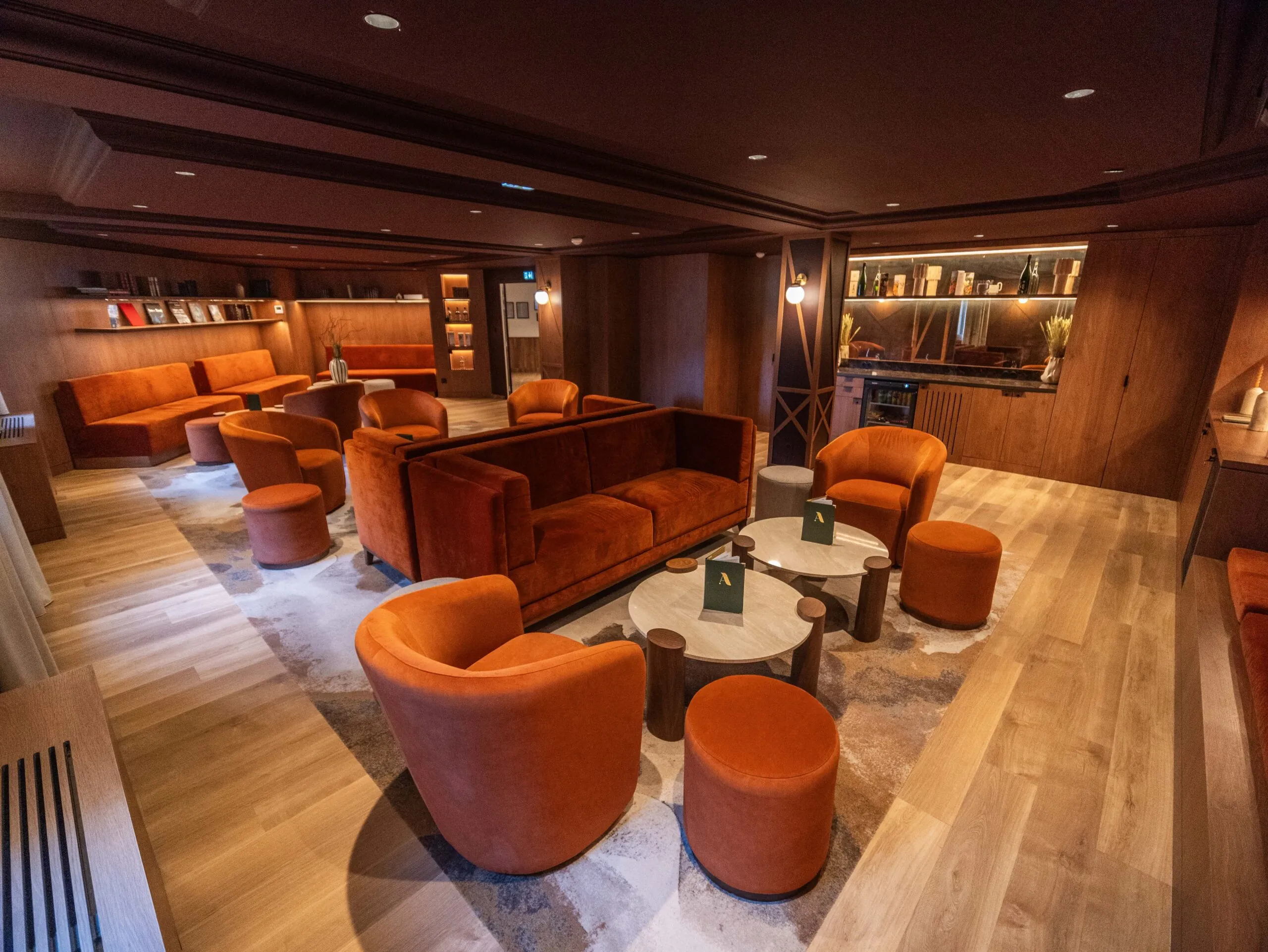 a cinema lounge area with a screen, sofas, armchairs, tables, a bookcase