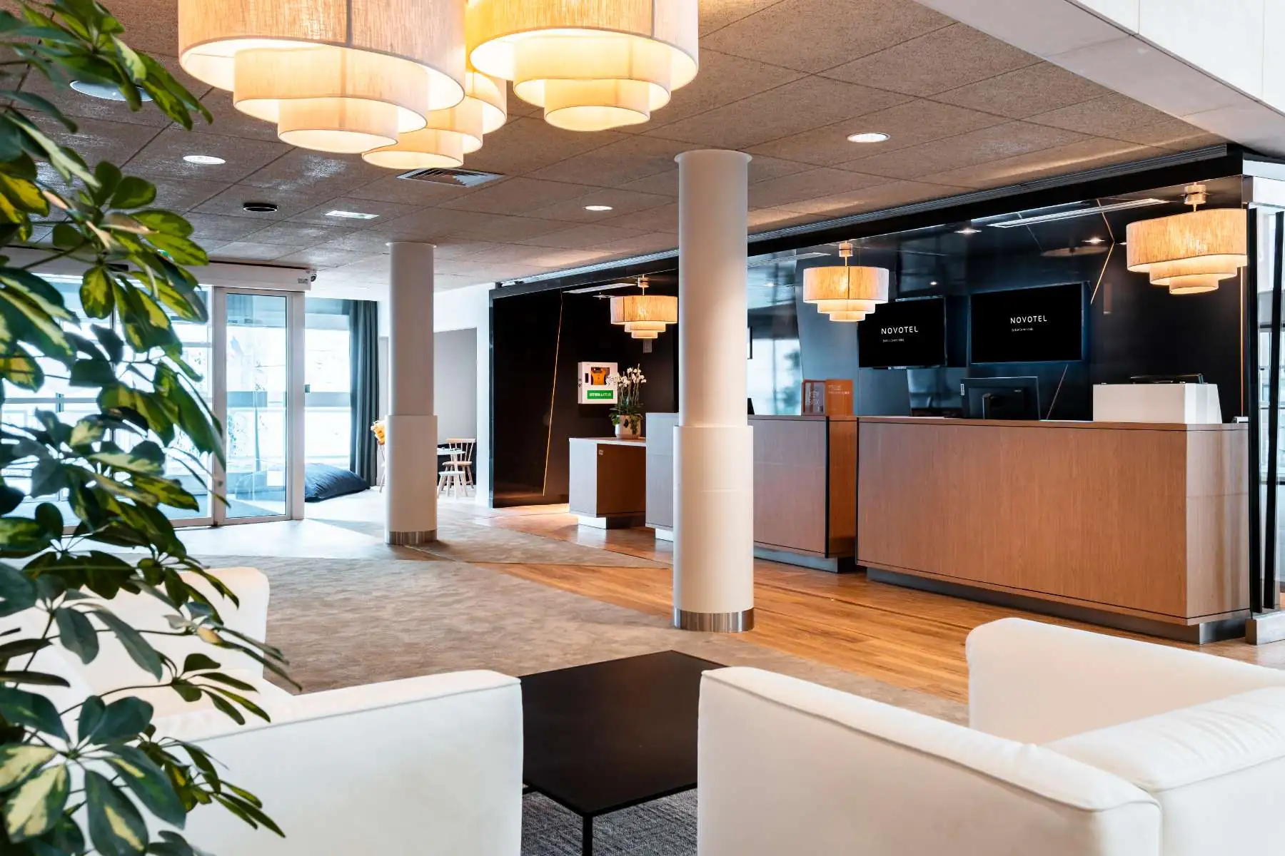 hotel lobby with a children’s play area, wooden reception desk, white leather armchairs and lights fixture made of three rings