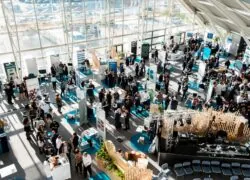 high-angle view of an exhibition room set up as a professional trade show, with exhibitors presenting their company and a screening area with rows of seats