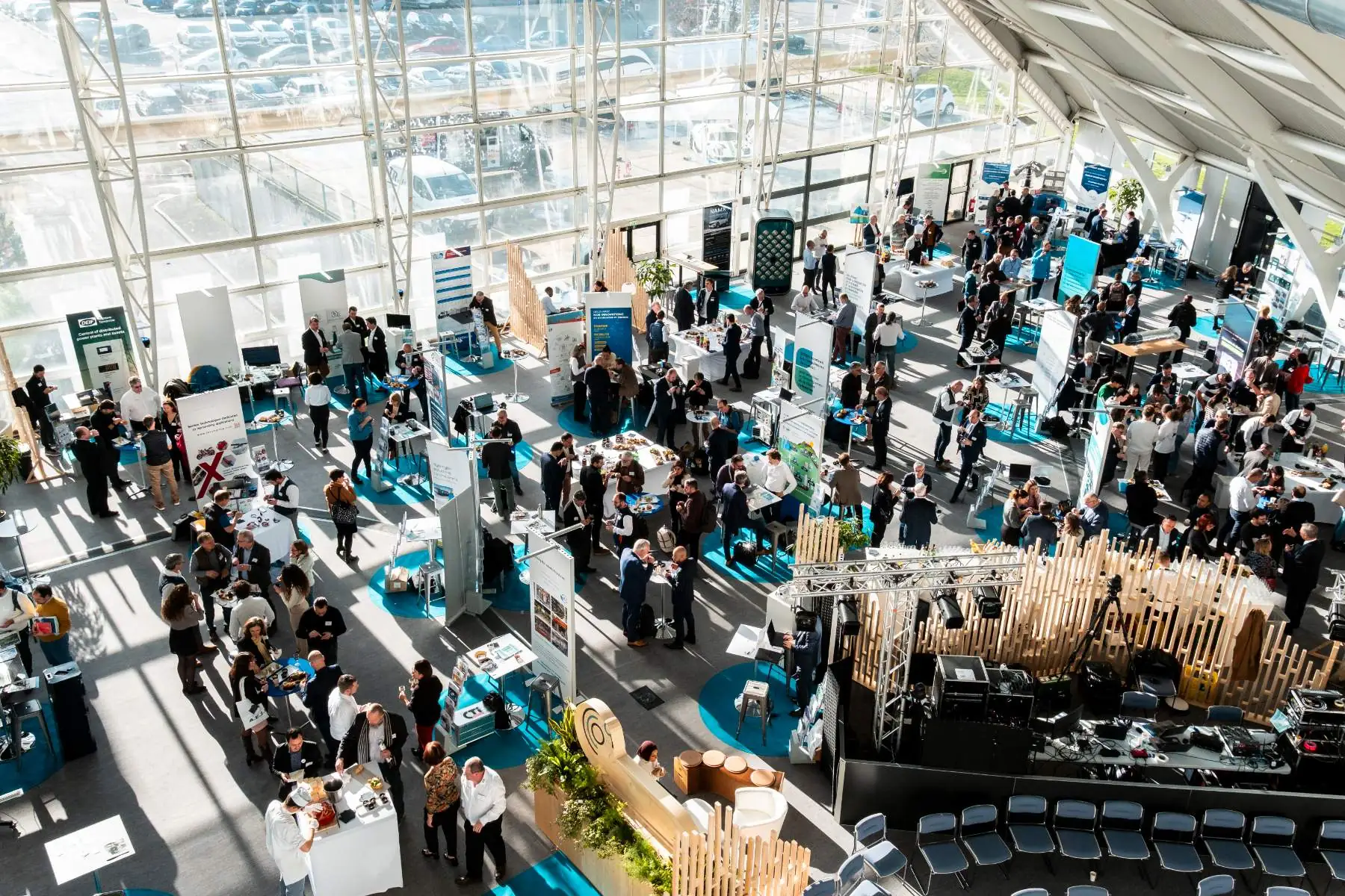 high-angle view of an exhibition room set up as a professional trade show, with exhibitors presenting their company and a screening area with rows of seats