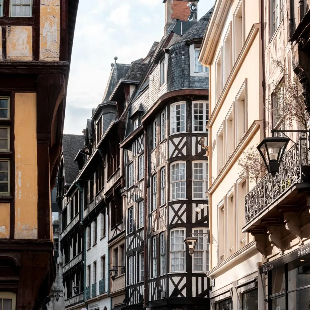 en::Photo of a building with typical Norman architecture, featuring exposed timber framing, balconies, and traditional decorative details. fr::Photo d’un bâtiment à l’architecture normande typique, avec colombages apparents, balcons et éléments décoratifs traditionnels.