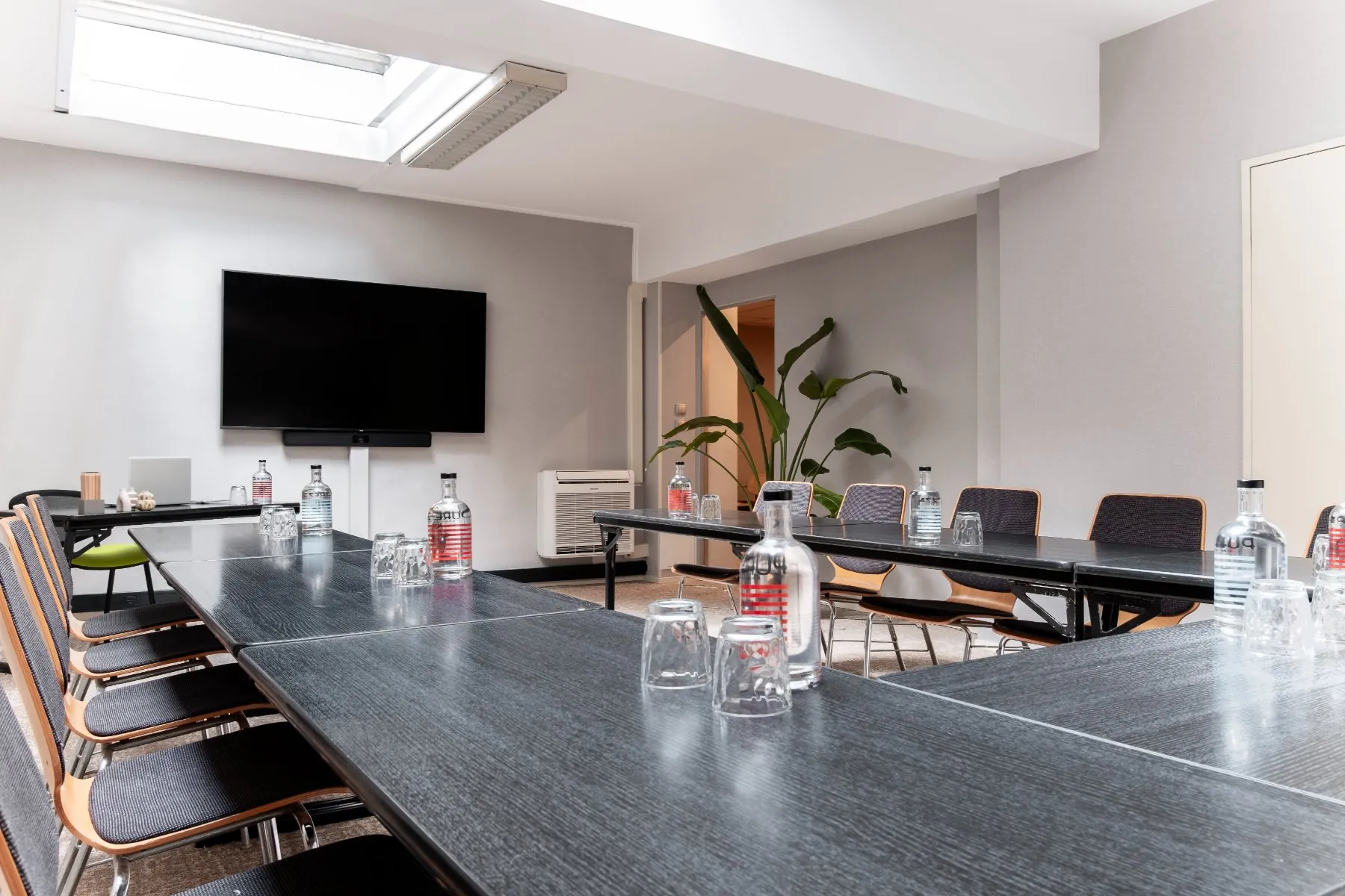 rows of chairs arranged in a U-shape meeting room, with a ceiling-mounted skylight
