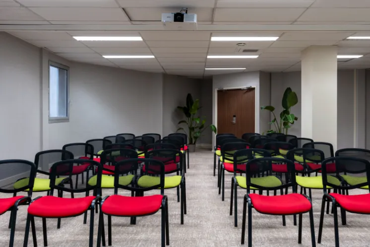 rows of chairs arranged in a meeting room, with a ceiling-mounted projector, captured from a different viewing angle