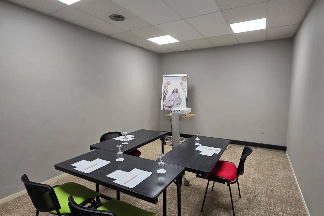 small-capacity meeting room arranged in a U-shape, with three desks and chairs in vibrant green and red tones