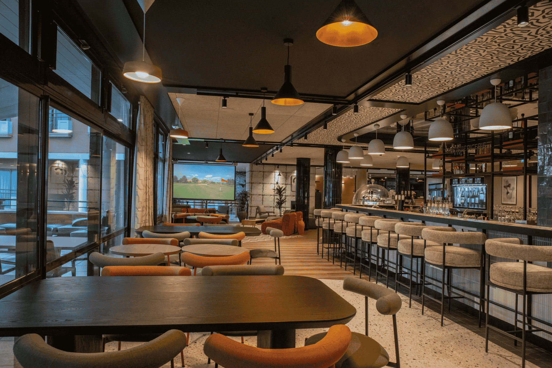 en::Set tables along the restaurant’s floor-to-ceiling windows overlooking the golf course and the pool, a central bar with seating on both sides, a wide counter for buffet or cocktail receptions facing the pool, and a lounge area with a screen at the entrance. fr::Tables dressées le long des baies vitrées du restaurant, avec vue sur le golf et la piscine, bar central avec fauteuils de chaque côté, large comptoir pour buffet ou cocktail et espace lounge avec écran à l’entrée