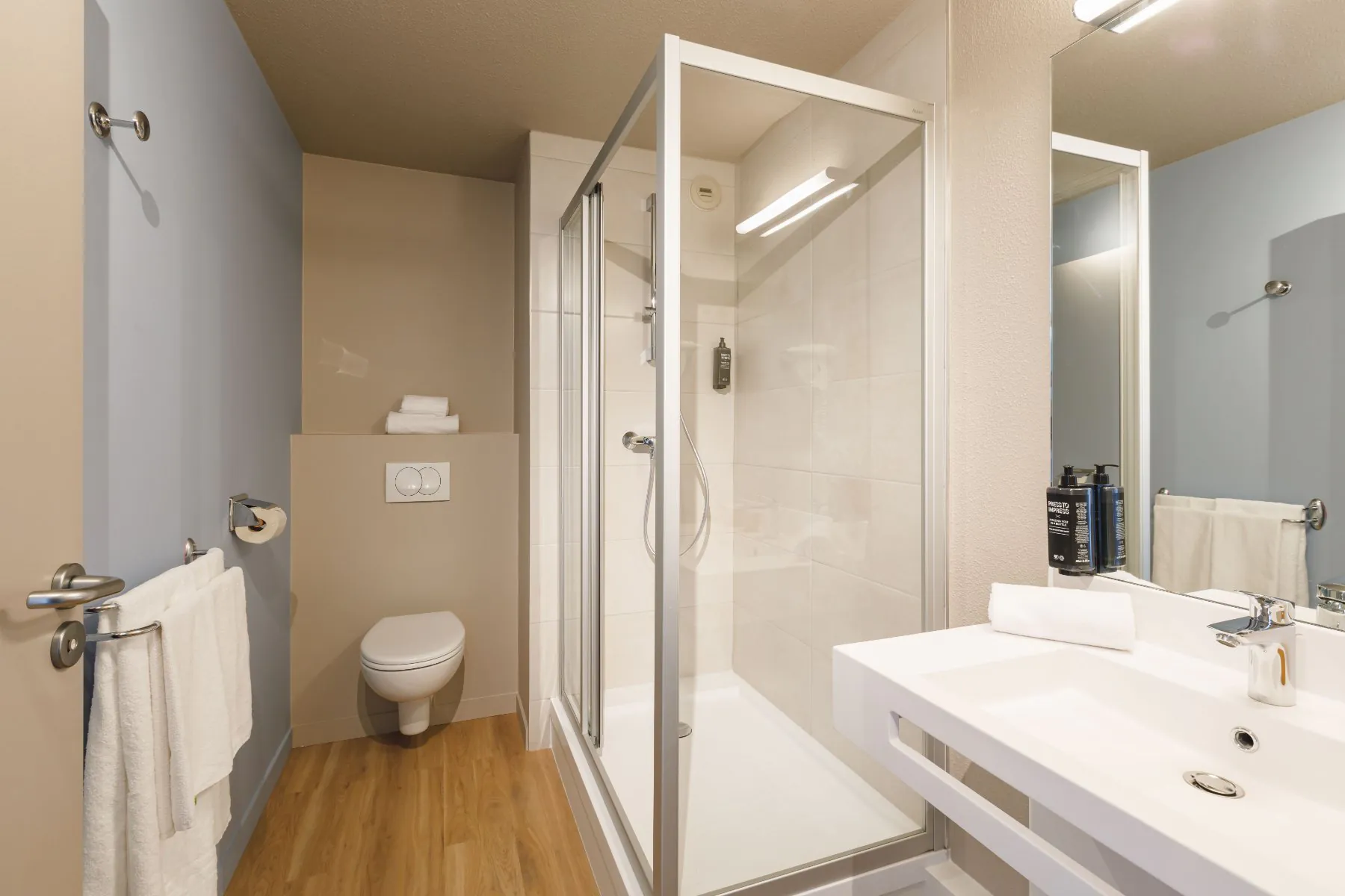 en::Shower room with wall-mounted toilet, rectangular sink and large mirror. fr::Salle de douche avec WC suspendu, lavabo rectangulaire et grand miroir.