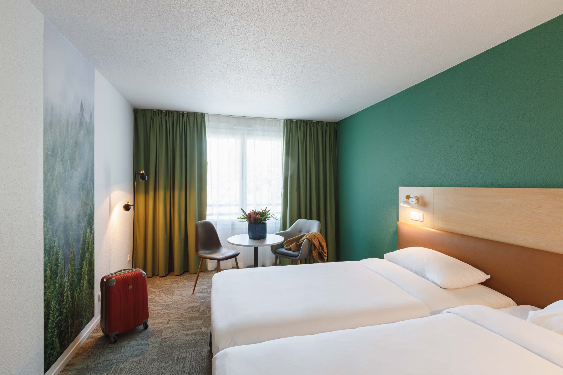 en::Twin beds with wooden and leather headboards, large wall photo of a forest, matching double curtains. fr::Lits twin avec têtes de lit bois et cuir, grande photographie de forêt sur le mur, doubles rideaux assortis.