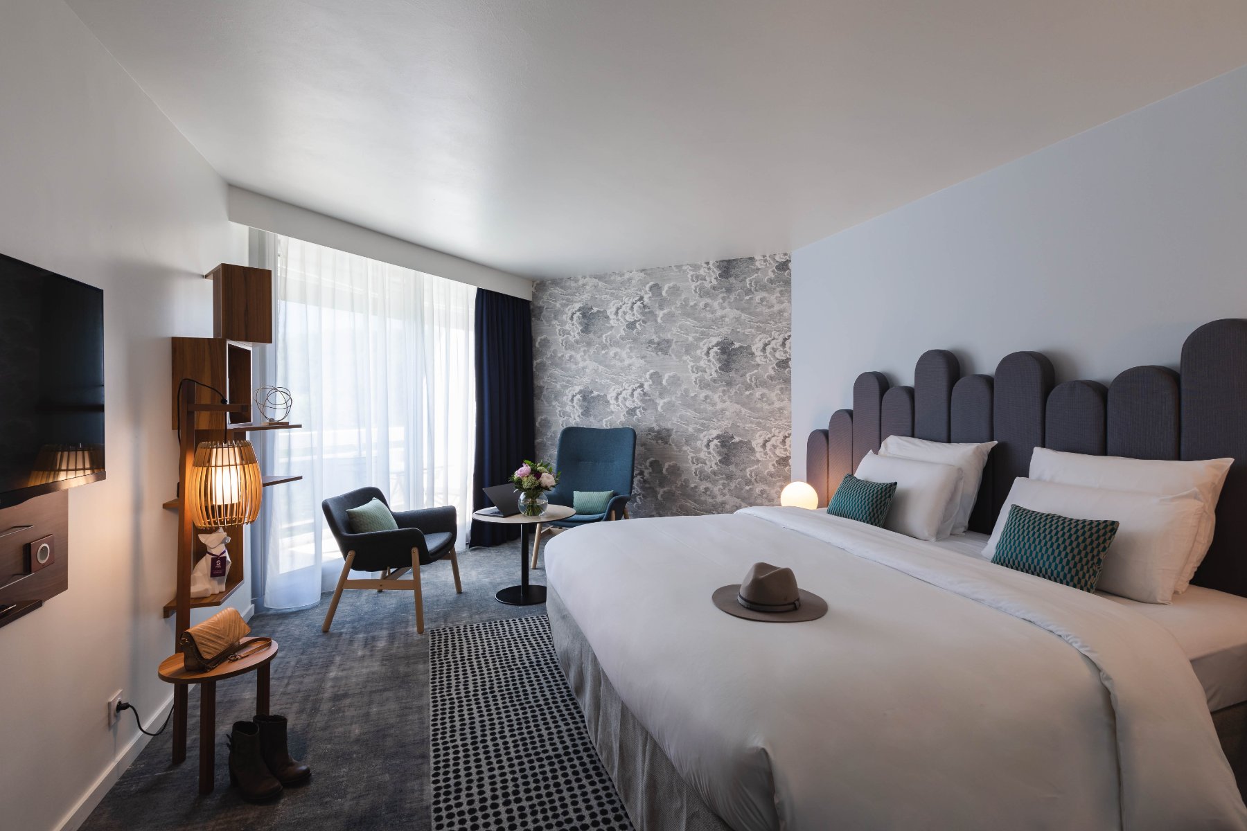 en::Large double bed, carpeted floor with rug, lounge area, wall-mounted TV and terrace. fr::Lit double grande largeur, moquette avec tapis, coin salon, TV murale et terrasse.