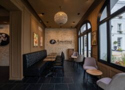 en::Leather sofas along a wall, square tables and black chairs opposite, with a view over the hotel’s inner courtyard. fr::Canapés en cuir le long d’un mur, tables carrées et chaises noires en face, avec vue sur la cour intérieure de l’hôtel.