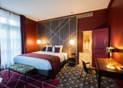 en::Long private corridor in perspective leading to a bedroom with a king-size bed, footrest, and a Second Empire-style desk. fr::Long couloir privatif en perspective menant à une chambre avec lit king size, repose-pieds et bureau de style Second Empire.