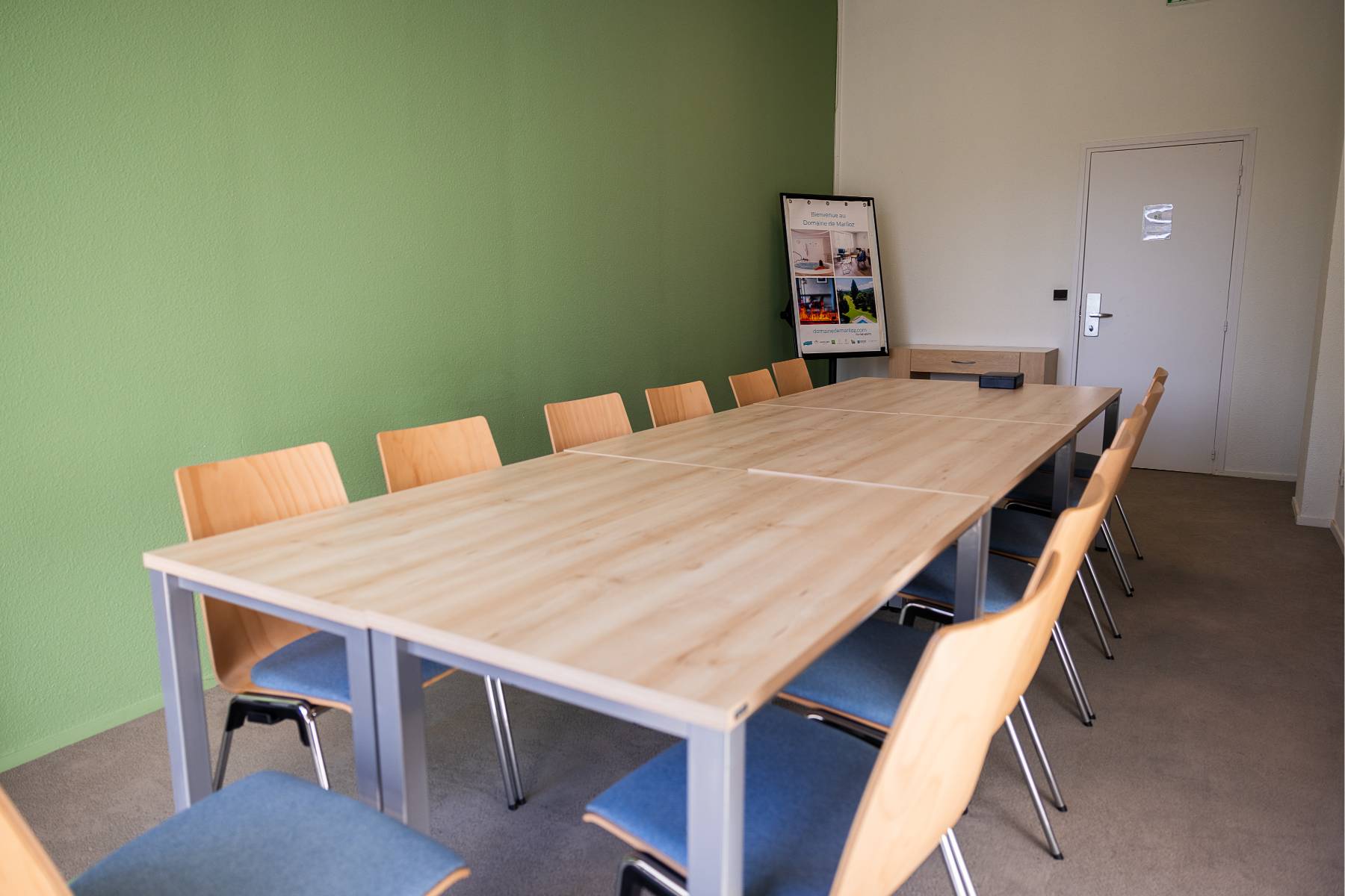 en::Fourteen chairs around tables in boardroom layout, toolbox on the table, console cabinet fr::14 chaises autour de tables en configuration board, boîte à outils sur la table, meuble console à proximité.