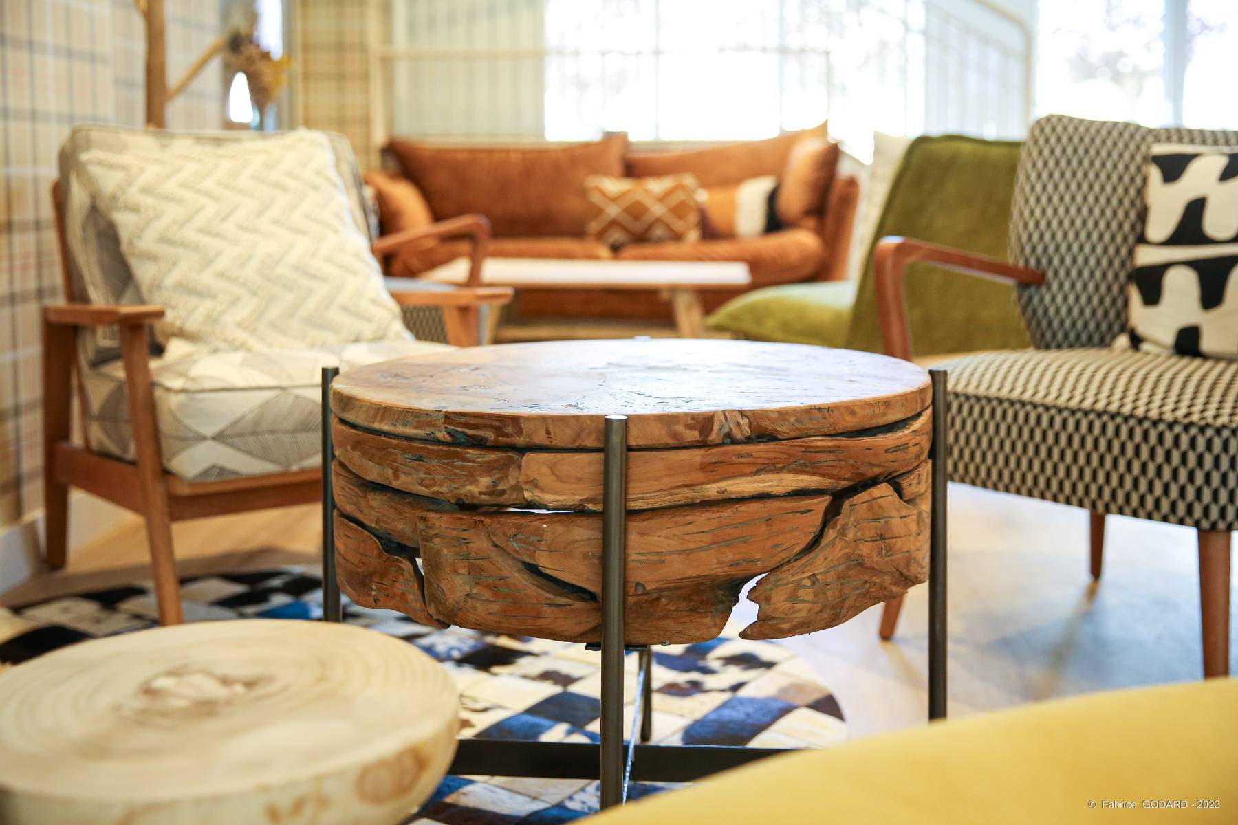 en::Brown sofas, black and white checkered chairs, round table and checkered tapestry, in an authentic and warm atmosphere. fr::Canapés marron, chaises à damier noir et blanc, table ronde et tapisserie à carreaux, dans un esprit authentique et chaleureux.