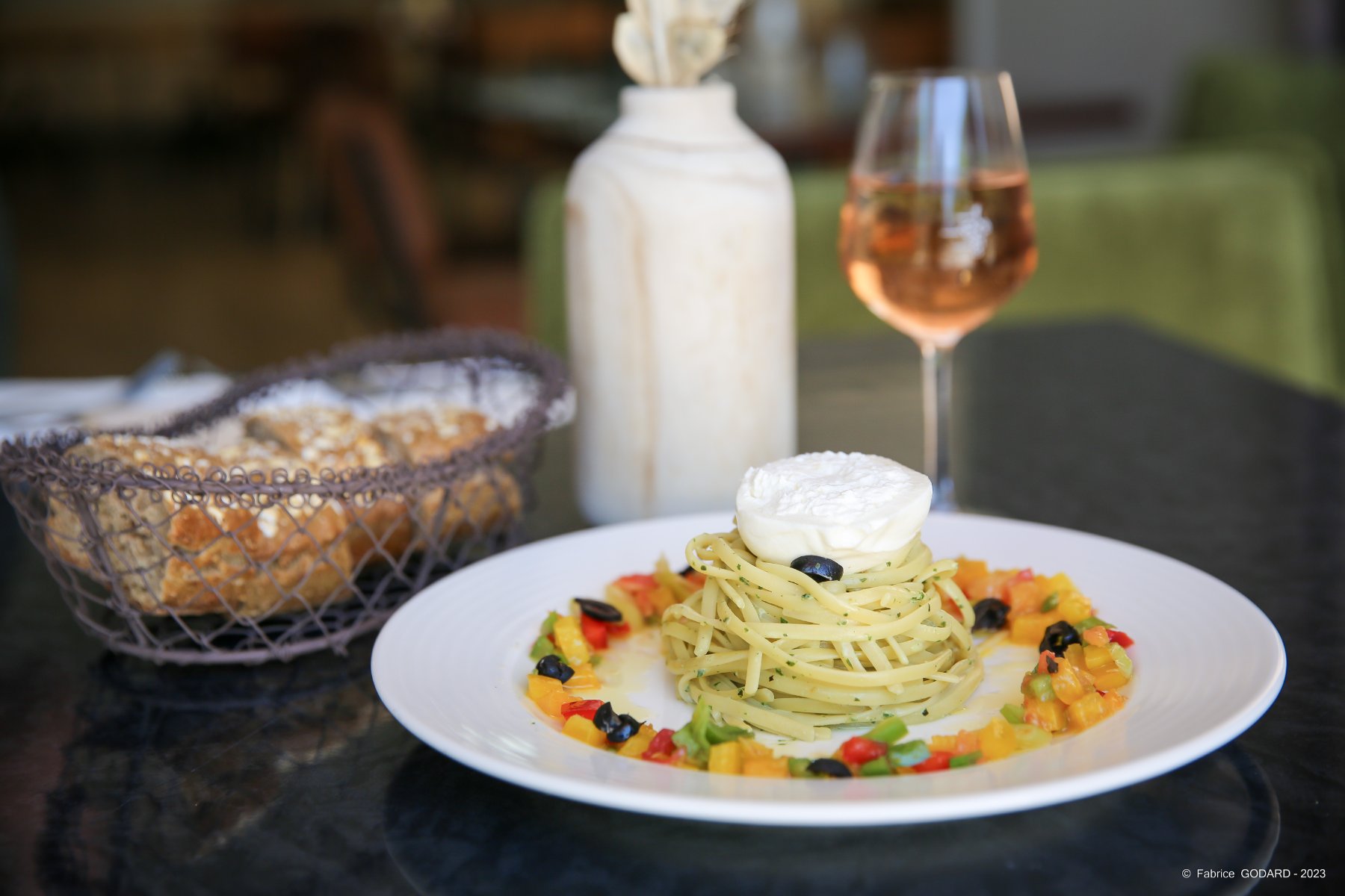 en::Julienned vegetables plated with a dome of pasta topped with mozzarella, served with rustic bread and a glass of wine. fr::Plat de légumes en julienne avec un dôme de pâtes surmonté de mozzarella, accompagné de pain rustique et d’un verre de vin.