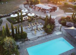 Vue aérienne des extérieurs de l'hôtel qui présente au premier plan une grande piscine rectangulaire et en fond la grande terrasse de l'hôtel