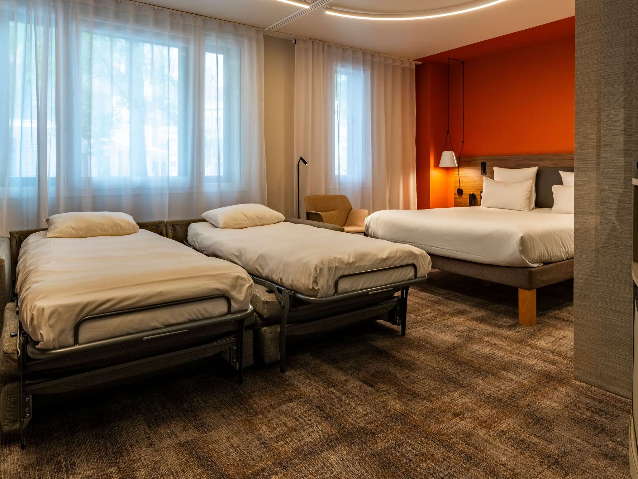 Suite with brown checkered carpet, red walls, a double bed and an open two-person sofa bed prepared as twin beds.