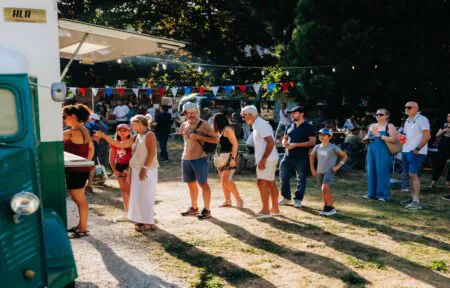 Espace guinguette sous un séquoia géant, avec un groupe de clients devant un food truck bar pour commander leurs boissons.