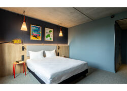 Une chambre à dominante bleue avec un large lit double au centre et une décoration évoquant le sport