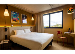 Cette photo d'une chambre lumineuse et coloré dévoile un large lit double et un petit coin bureau
