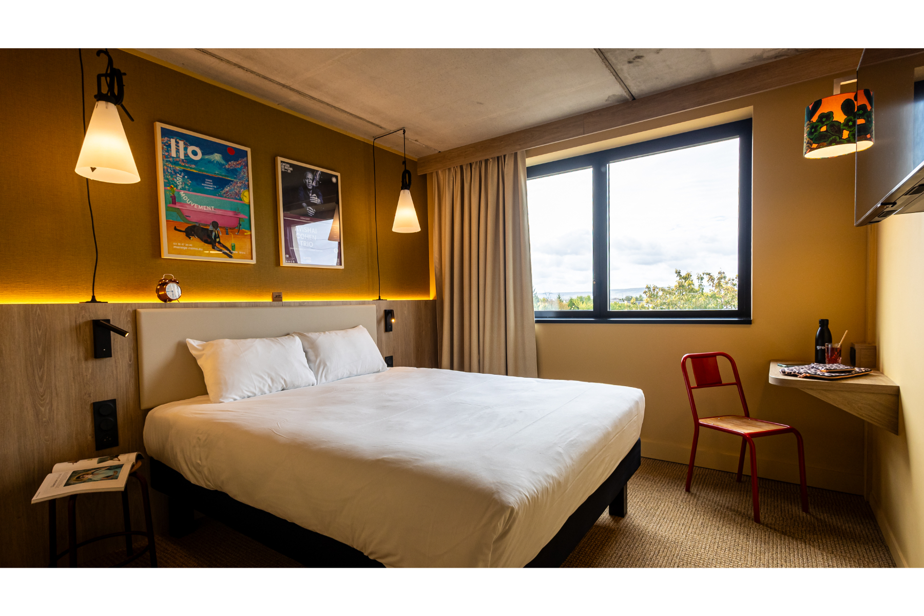 Cette photo d'une chambre lumineuse et coloré dévoile un large lit double et un petit coin bureau
