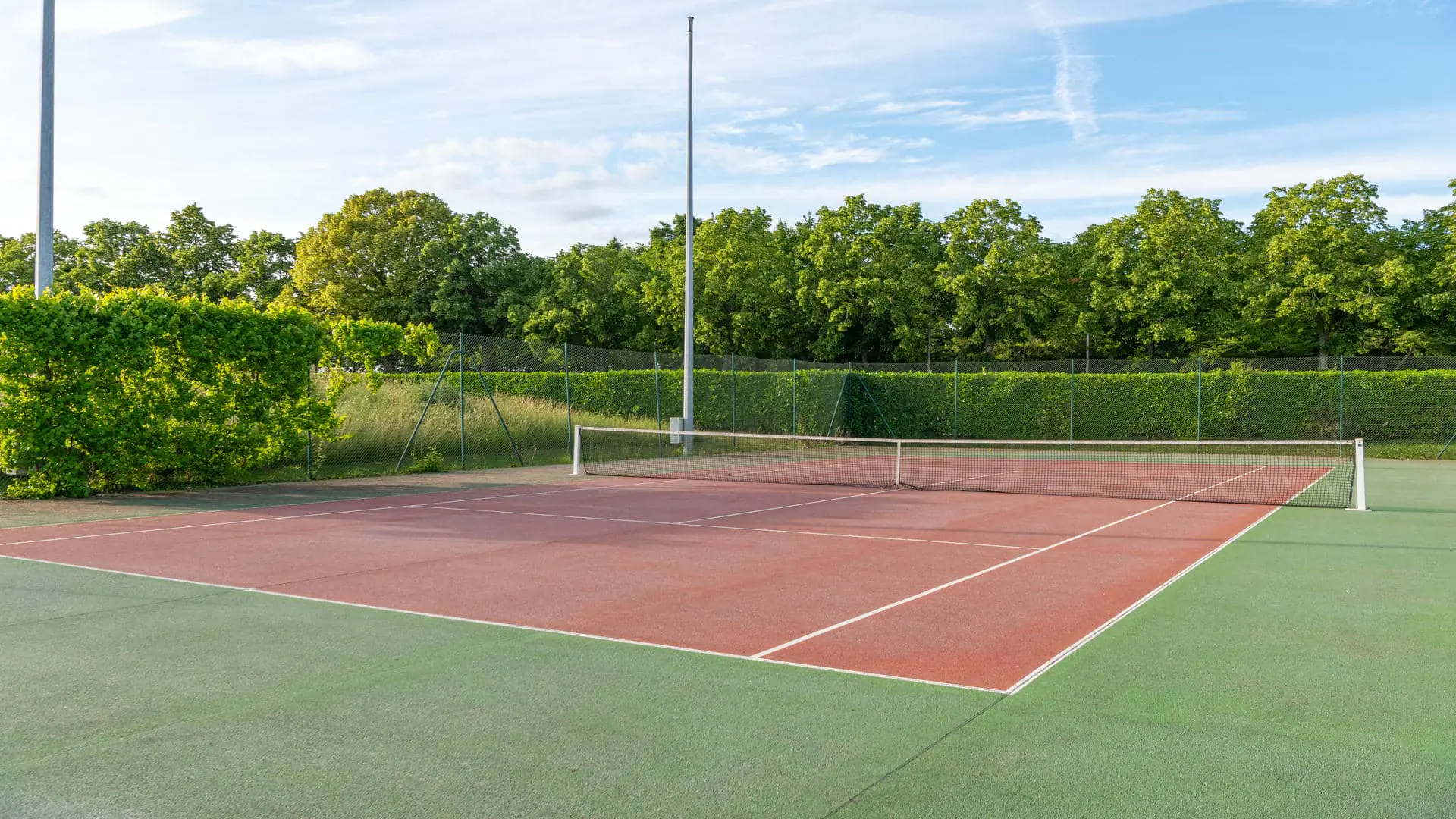ennis court surrounded by greenery under a blue sky for a sports team-building activity.