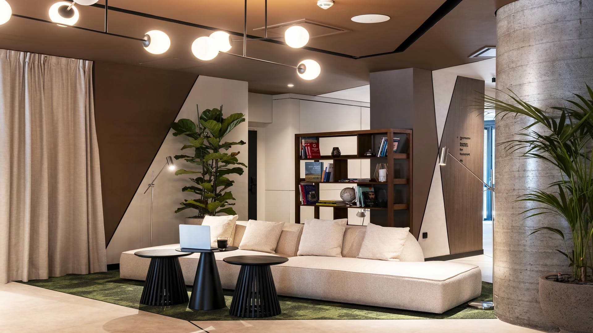Lobby with bookcase, light beige sofa and coffee area in a seminar venue in Grenoble.