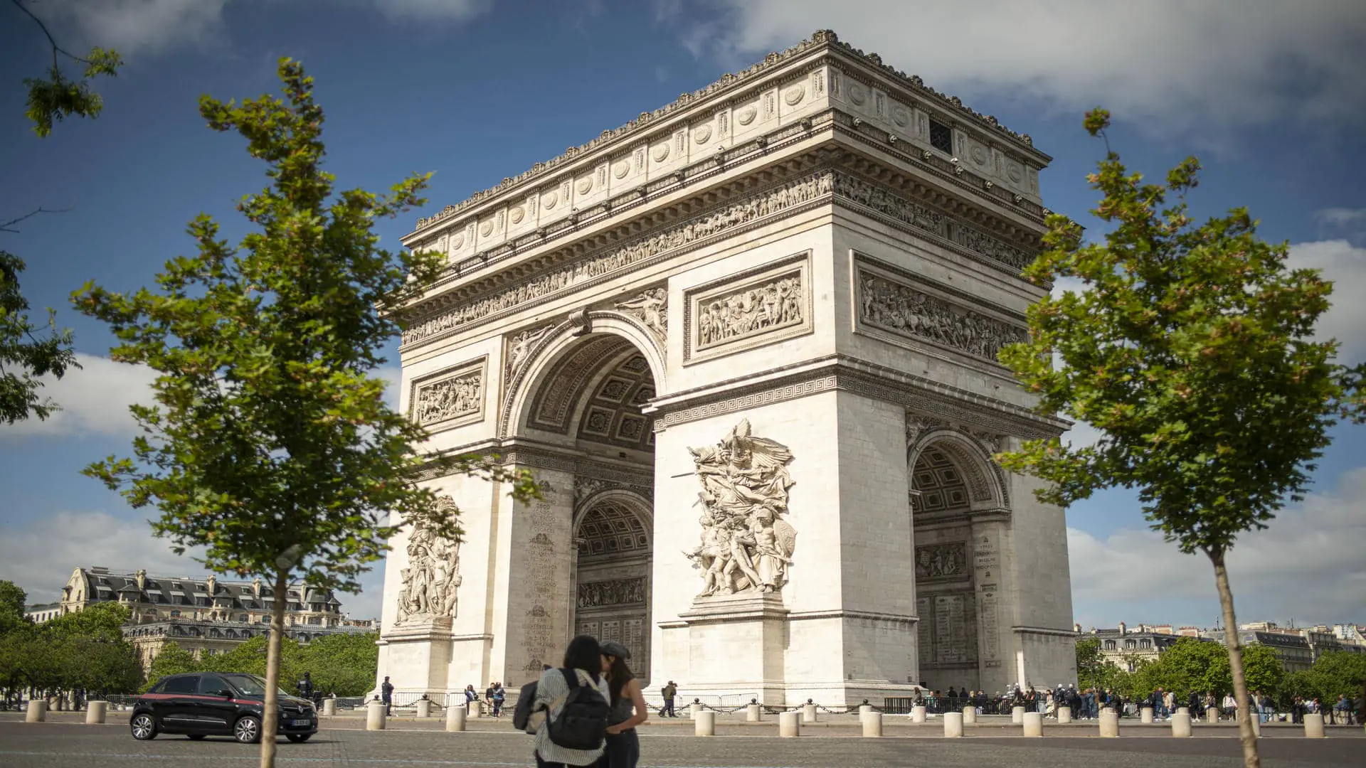 Arc de Triomphe photographié sous un ciel bleu, avec végétation printanière au premier plan.