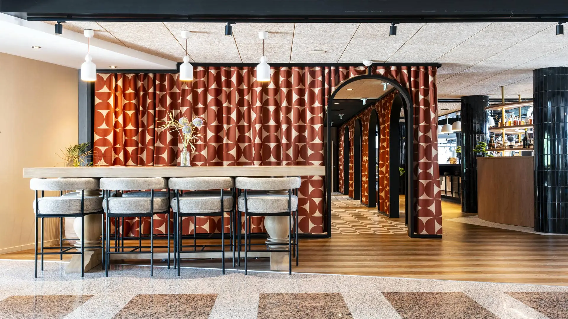 Accès design depuis le lobby vers les salles de réunion du rez-de-chaussée de l’hôtel séminaire, encadré par des rideaux occultants et des contours de porte noirs arrondis.