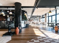 Restaurant séminaire avec bar occupant une grande partie de la salle, vue sur la piscine, la terrasse et le golf, dans un espace très design.