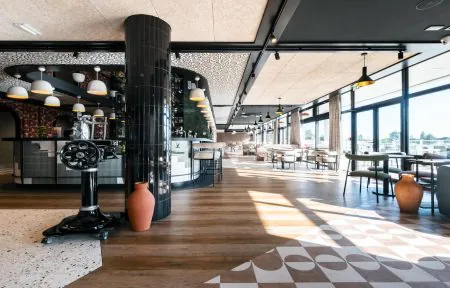 Restaurant séminaire avec bar occupant une grande partie de la salle, vue sur la piscine, la terrasse et le golf, dans un espace très design.