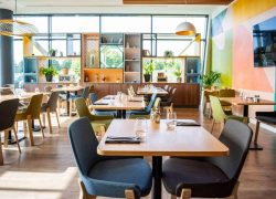 La salle de restaurant dédiée aux séminaires présente des murs, des chaises et des étagères décorés dans des tons rose, vert et bleu.