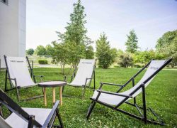 Des transats sont installés sur la pelouse verdoyante du jardin, devant le bâtiment en U de cet hôtel pour séminaires proche de l’aéroport.