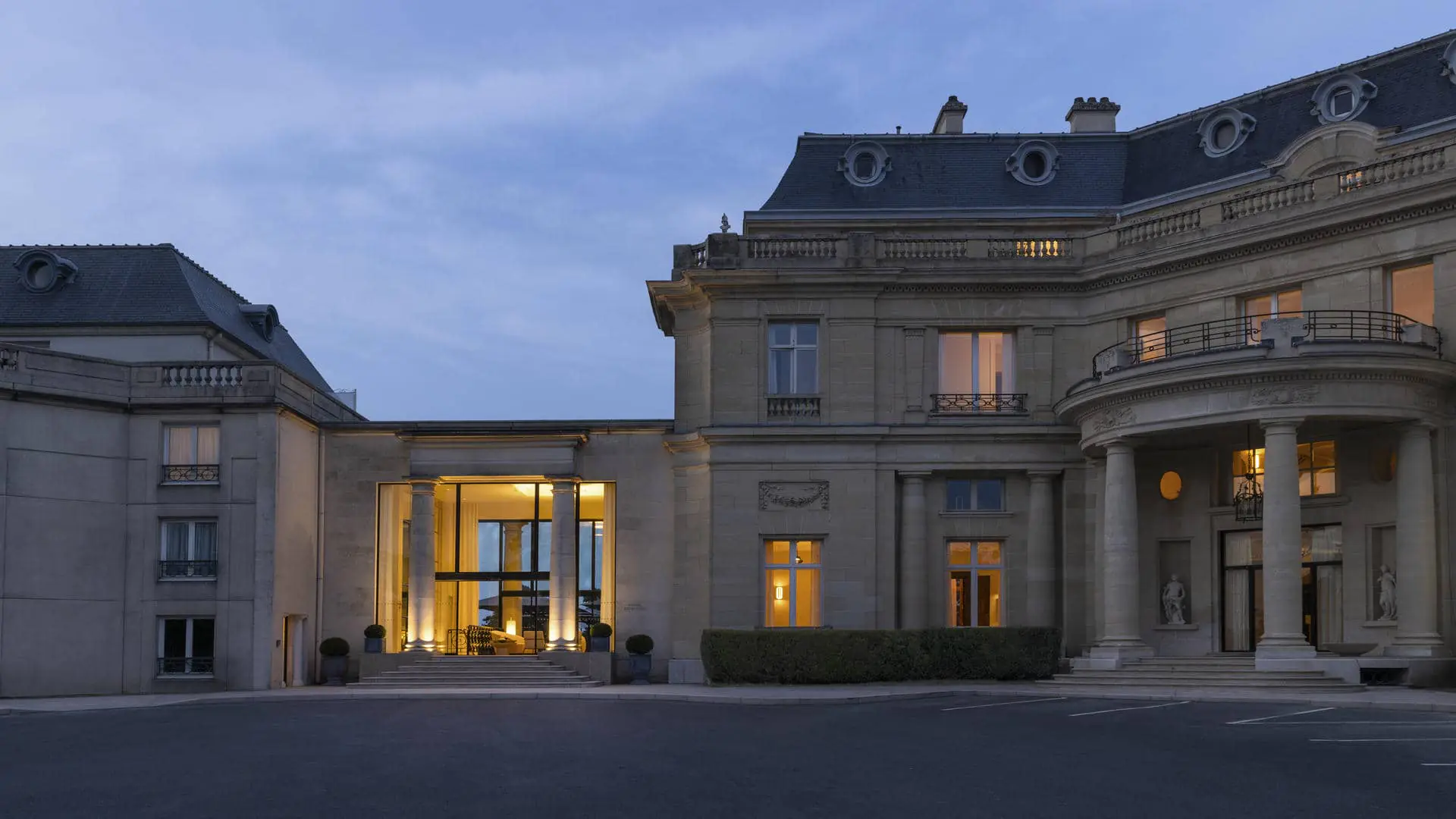 Château façade at night with lighting highlighting the two floors and the ground-floor restaurant terrace.
