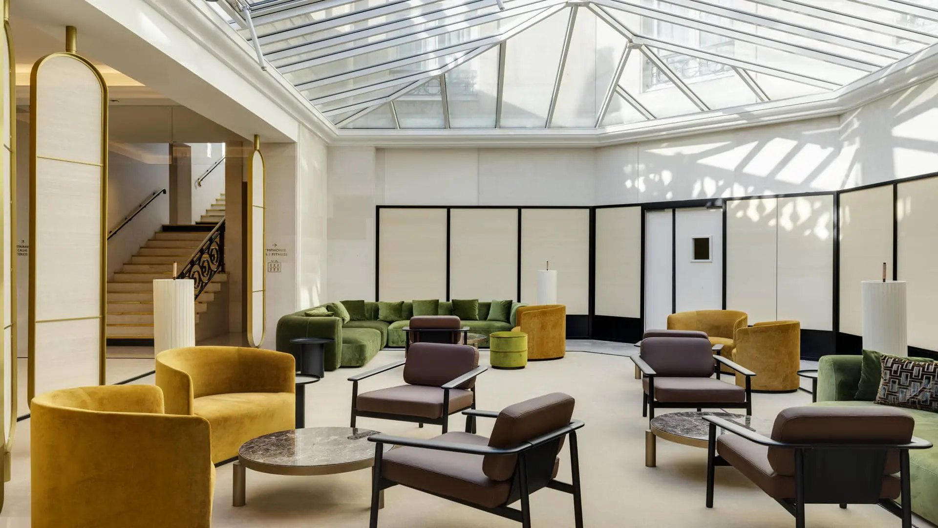 Glass-roofed patio with sofas, armchairs and coffee tables, set up as a seminar break and cocktail area.