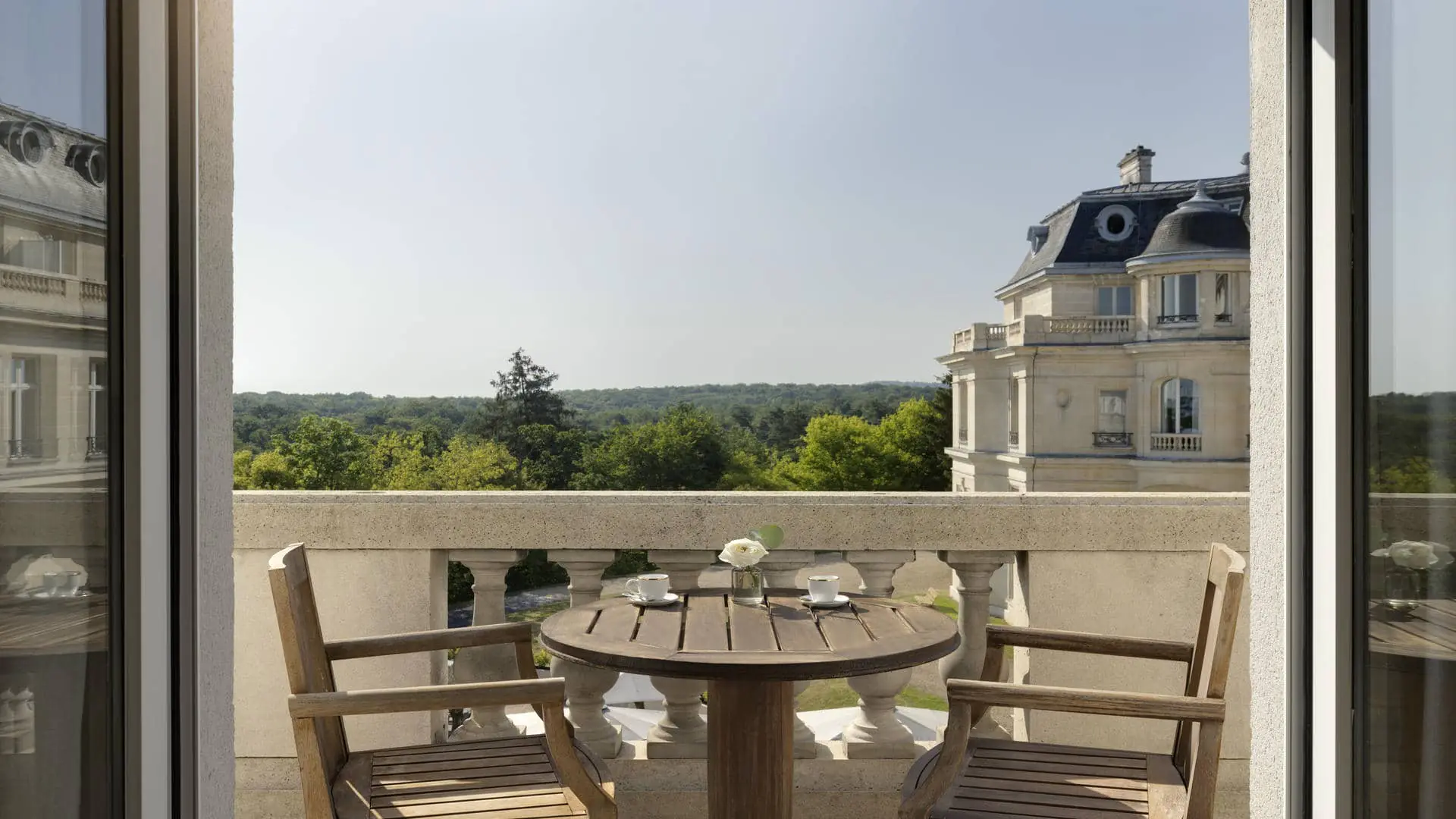 Bedroom balcony with teak furniture, overlooking the forest and the château.