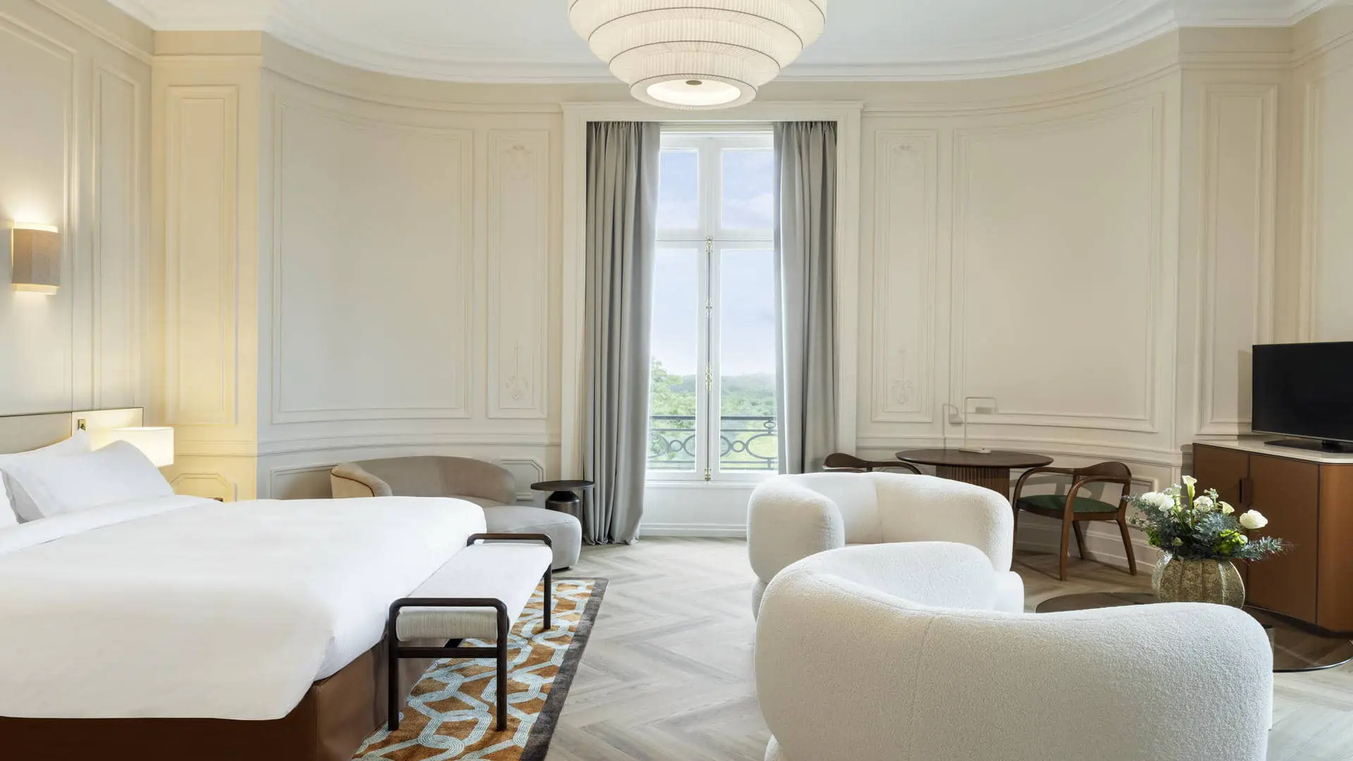 Suite with an extra-large double bed, large French doors overlooking the forest, white fabric armchairs, tables and additional seating.