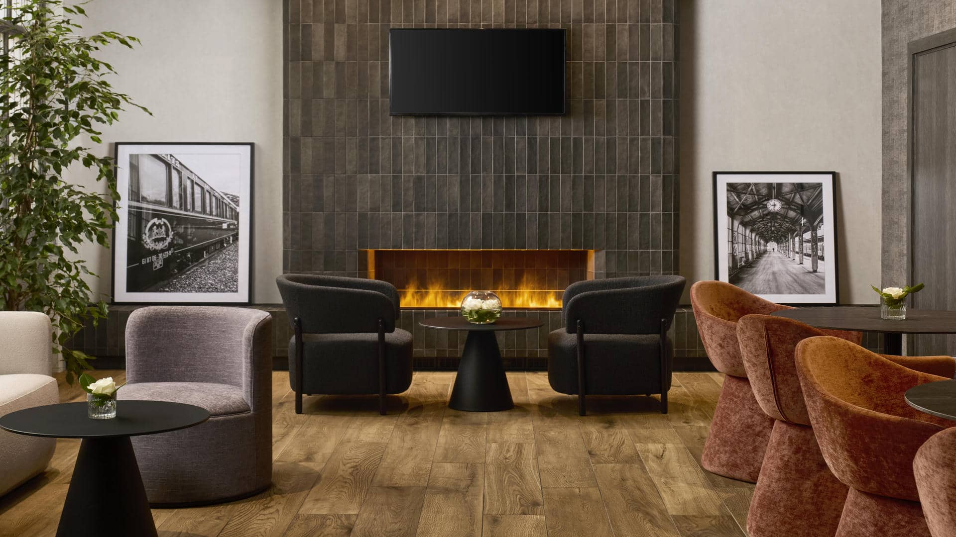 Le bar de l’hôtel séminaire se compose d’une cheminée, de photographies en noir et blanc, de fauteuils noirs ou terracotta et de petites tables basses noires.