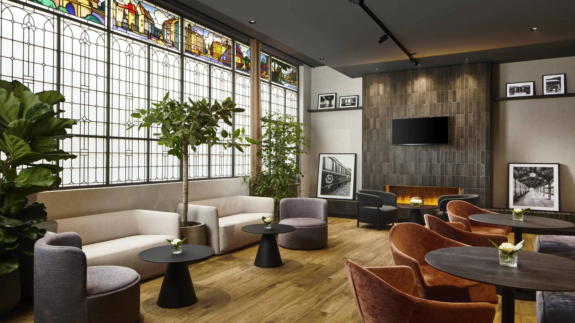 Le bar de l’hôtel séminaire se compose, à droite, de vitraux, de canapés séparés par des plantes, avec tables basses noires devant chaque assise, d’une cheminée et, en face, de fauteuils noirs ou terracotta disposés autour de petites tables basses noires.