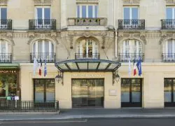 façade haussmanienne avec en rez de chaussée l'entrée du NH Gare de l'est, encadrée de drapeaux, à sa gauche entrée d'un restaurant avec en enseigne vente à emporter