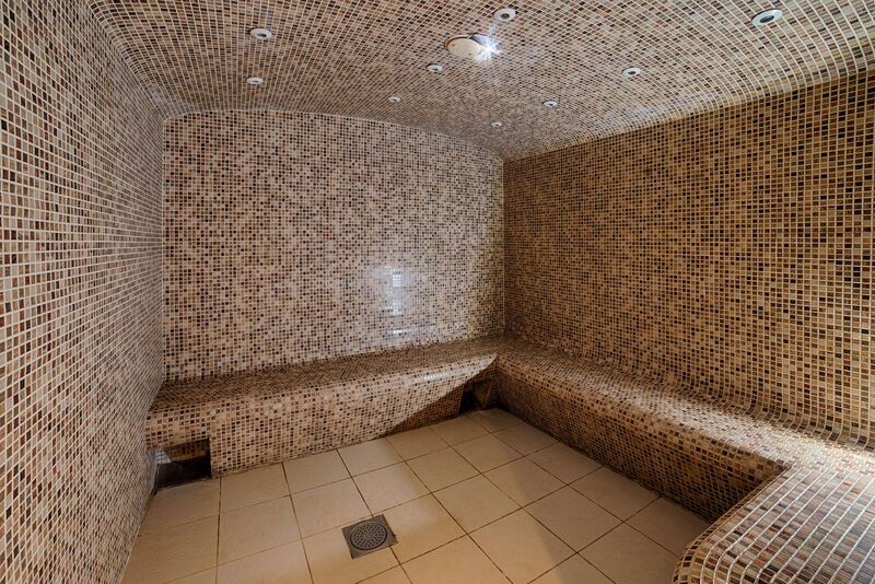 en::a spacious curved sauna in a seminar hotel, fully tiled from floor to ceiling fr::grand sauna d’un hôtel séminaire, entièrement carrelé du sol au plafond, à la forme arrondie