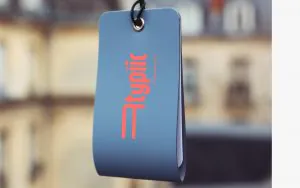 Dark teal leather room key holder with the Atypiic logo in bright coral pink.
