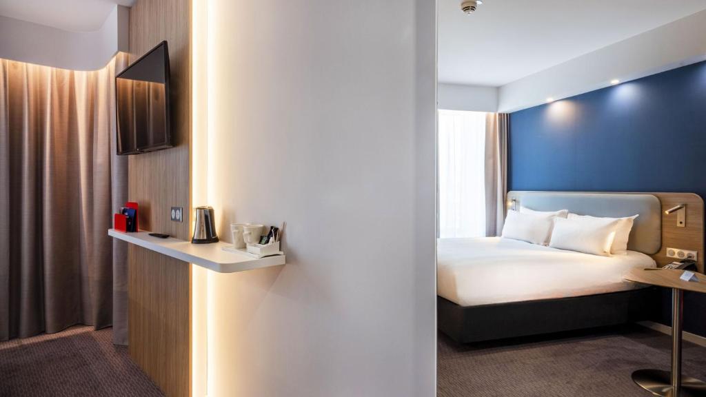 Room with blue walls, brown carpeting, and a partition wall separating the different sleeping areas, with a double bed on one side and twin beds on the other.